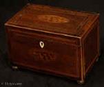 TC541: Inlaid mahogany two compartment  tea caddy circa 1790. The top and front have  central  oval marquetry medallions depicting  conch shells. Inside there are two compartments with supplementary lids with turned bone pulls. in the 18th century manner the lids do not have supports but would be expected to sit on the tea. The orchestration of the inlays is complex. The top has the central cartouche inlaid in a panel of well figured flame mahogany. This is framed by inlaid stringing in light and dark woods and a cross banding of mahogany. The caddy is edged in boxwood having facings to the bottom and the lid. The caddy stands on cast gilded brass feet.