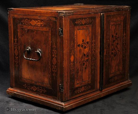 Rare South German  marquetry  table cabinet the hinged doors opening to a compartmentalized interior with nine drawers. The outside door panels are inlaid with depictions of birds and flowers.  The  inside   intarsia depicts quirky  architectural landscapes. Lorenz Stoer's Geometria et Perspectiva, which was published in 1567 inspired intarsia workers to execute work featuring buildings. They experimented with perspective often imbuing the designs with a touch of Moorish fantasy. The intarsia workers were mostly settled in Augsburg. Augsburg was a cabinet making centre since the beginning of the 14th C.   