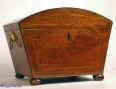 A Regency box with tapering sides  and domed top veneered  with beautifully figured mahogany  inlaid with boxwood in a restrained classical pattern, and framed with an  elaborate purfling  of boxwood and ebony with a crossbanding  of kingwood,  and edged with ebony, having gilded brass lion drop side handles  and standing on turned mahogany bun feet.  Inside the box has been been relined with hand made marbled paper and grey velvet. It has a replacement liftout tray which makes it suitable for jewelry and sewing circa 1810.  Enlarge Picture